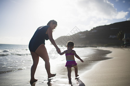 母亲和女儿手牵在海上行走图片
