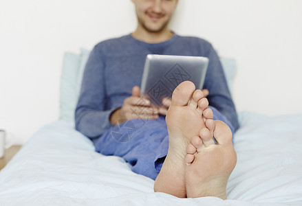 成人中年男子用数字平板电脑躺在床上图片