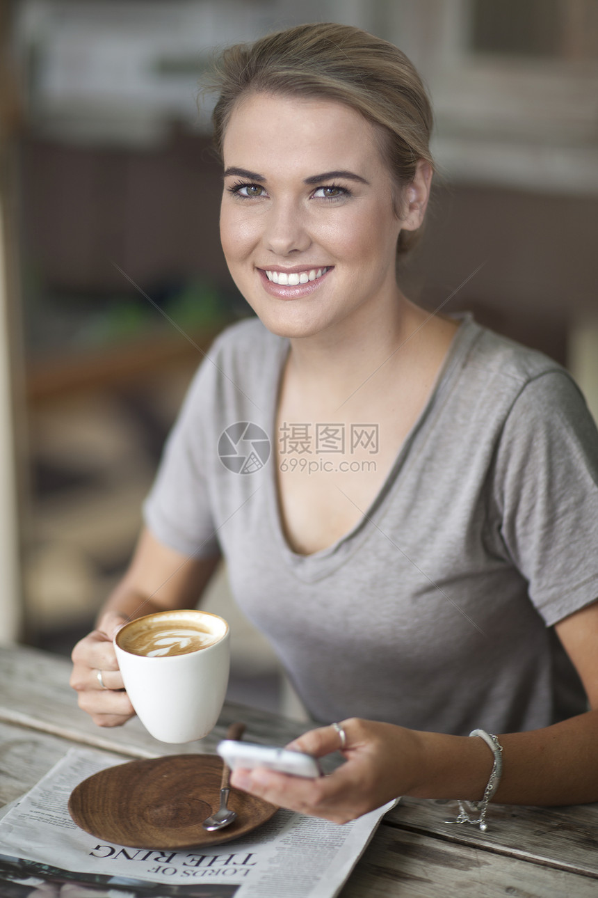 在咖啡馆喝咖啡玩手机的青年女性图片