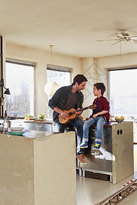 爸爸和小儿子在厨房里弹吉他图片
