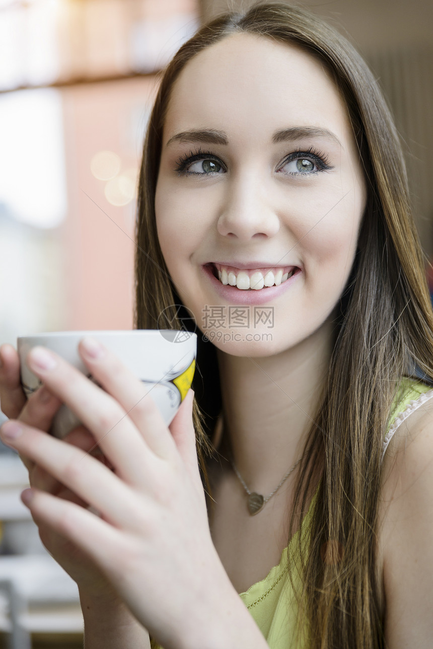 在咖啡馆内喝咖啡的年轻女子近景肖像图片