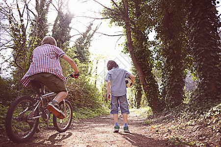男孩在森林路上骑自行车图片
