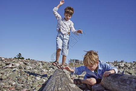 两个男孩在海滩上玩平衡木图片