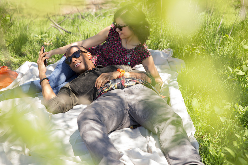 靠在公园野餐毯子上的年轻夫妇图片