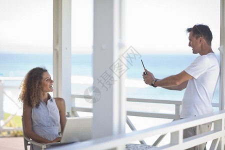 两人在海滩别墅阳台上拍照图片