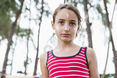 脸上涂着防晒霜的年轻女孩肖像背景图片