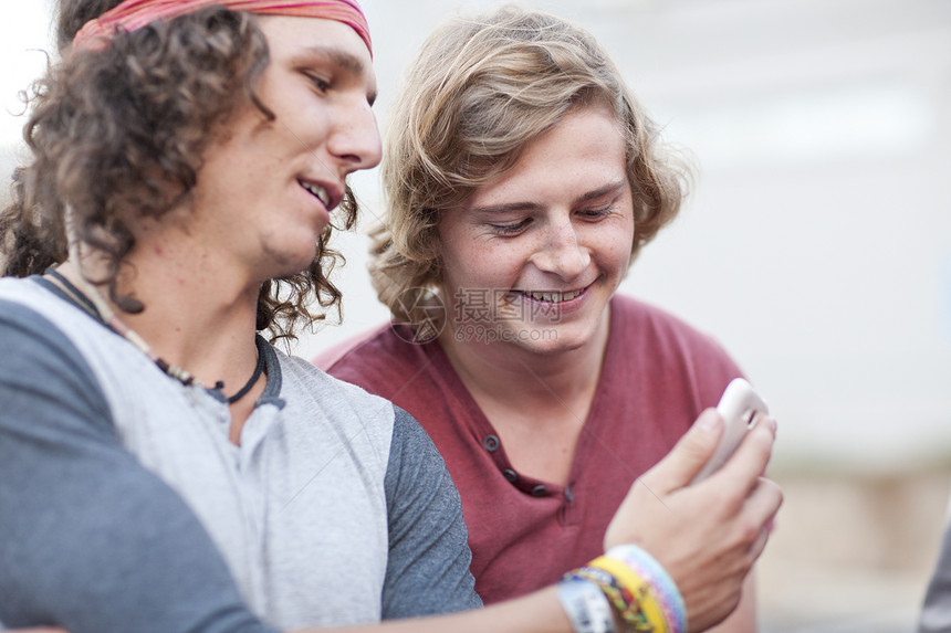 两个年轻男朋友在看智能手机图片