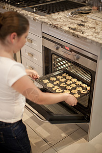 少女在烤箱中放置饼干盘图片