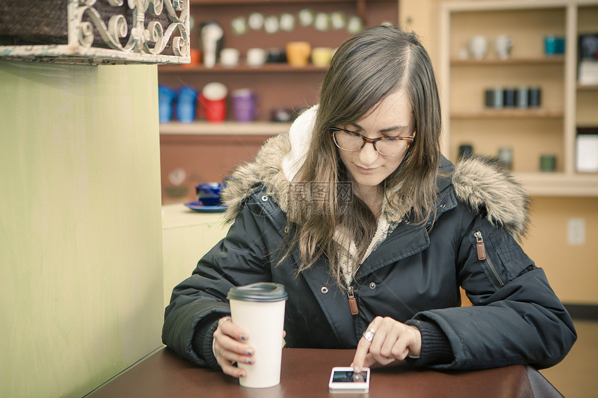 中成年女子在咖啡厅里用智能手机发短信图片