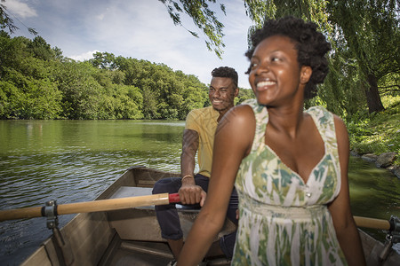 泛舟于湖上在公园湖上划船的年轻夫妇背景
