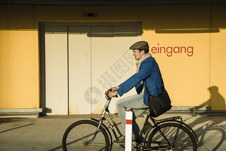 沿城市街道骑自行车的青年男子图片