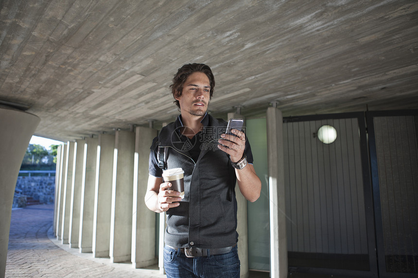中年男人在城市地下通道使用智能手机发短信图片