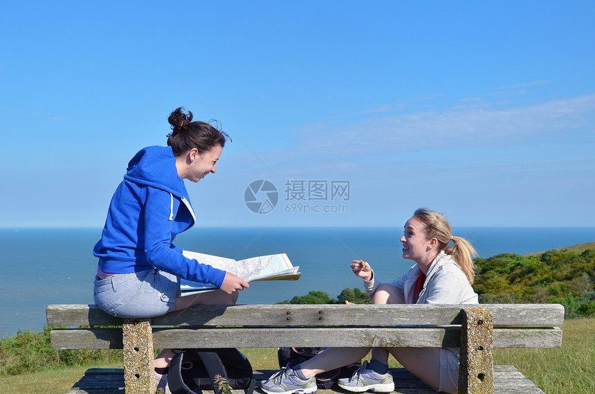 两名年轻妇女坐在路边的长椅上图片