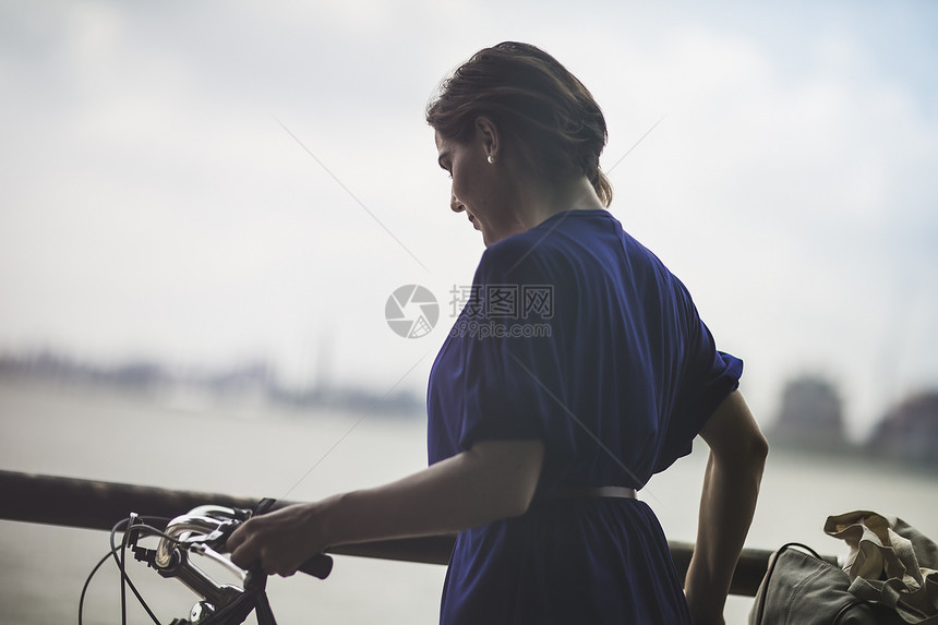 河边骑自行车的成年女性图片