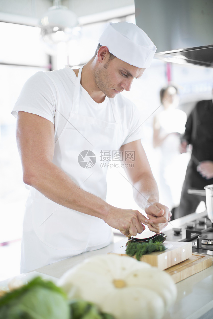 在商业厨房使用草药的男厨师图片