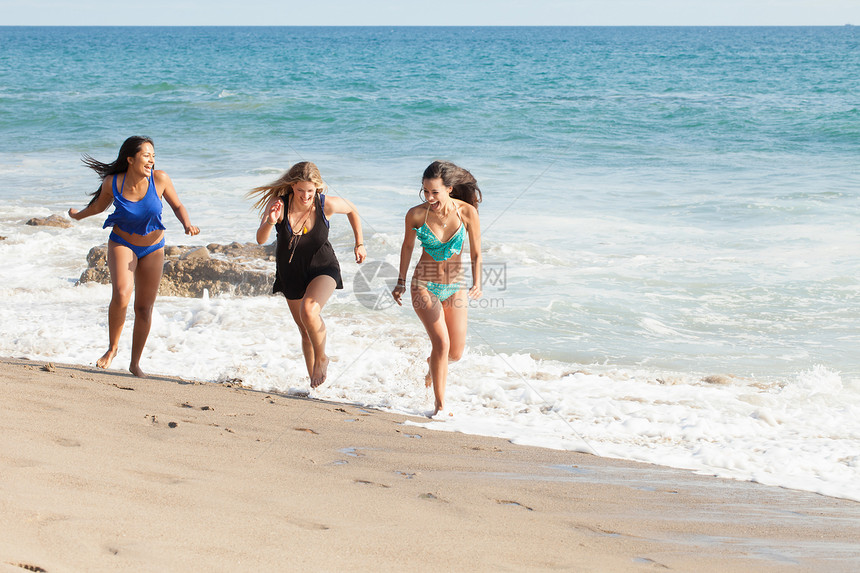 三名年轻妇女在美国加利福尼亚州马里布海滩上奔跑图片