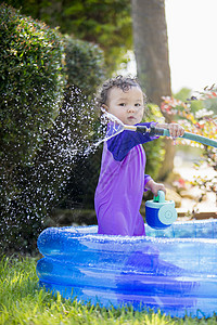 一个在游泳池里玩水管的女婴 图片