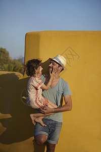 父亲抱女儿靠墙站立图片