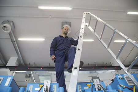 工业厂房梯子上的工人图片