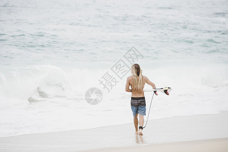 拿着冲浪板走在海边的男人图片