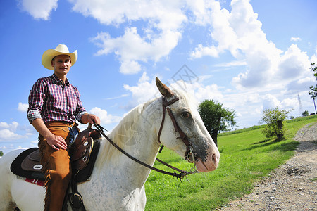在农村路上骑马的牛仔装男子背景图片