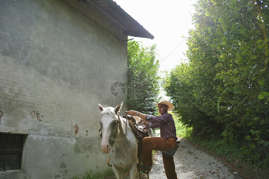 年轻人在谷仓外骑马图片