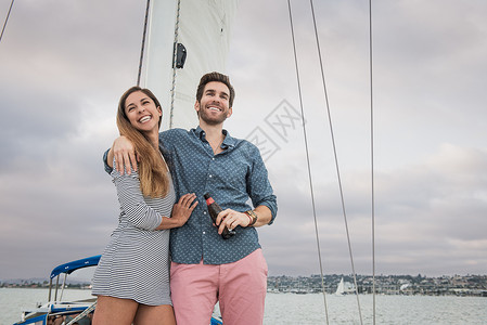 在帆船上搂着妻子微笑的男子图片