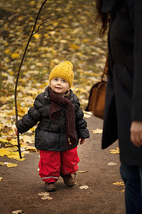 穿着冬装手拿树枝走路的小孩子图片