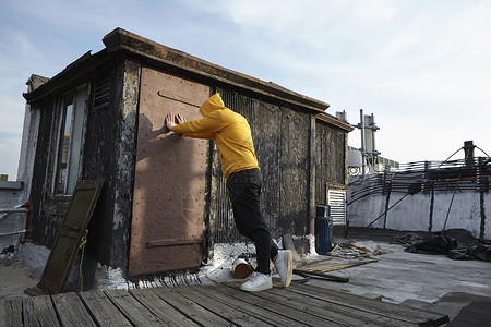 年轻人撑在屋顶墙壁向下看图片