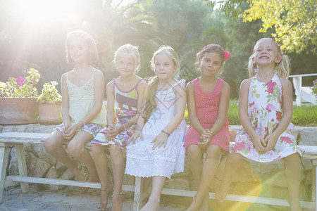 5名女孩坐在花园长椅上的肖像图片