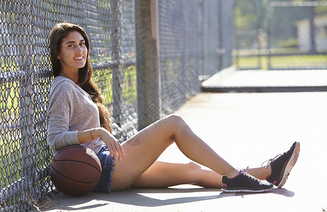 坐在铁丝栅栏旁的篮球少女图片