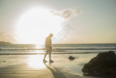日落成年男子在海滩上行走图片