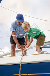 男孩帮爷爷拉帆船上的绳高清图片