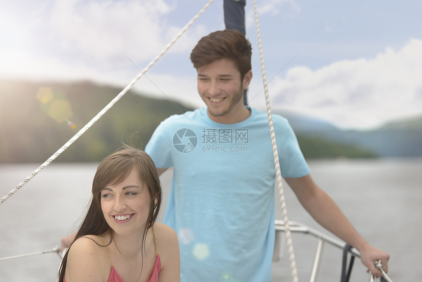 年轻夫妇在明光照耀的湖上游艇图片