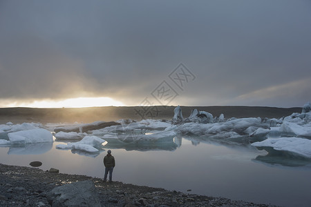 一个人站在海滩上面对结冰的湖水图片