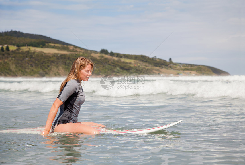坐在海上冲浪板的年轻女子肖像图片