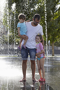 父亲和两个女儿在西班牙马德里的泉水中玩耍图片