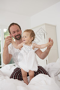 父亲在床上和女婴玩图片