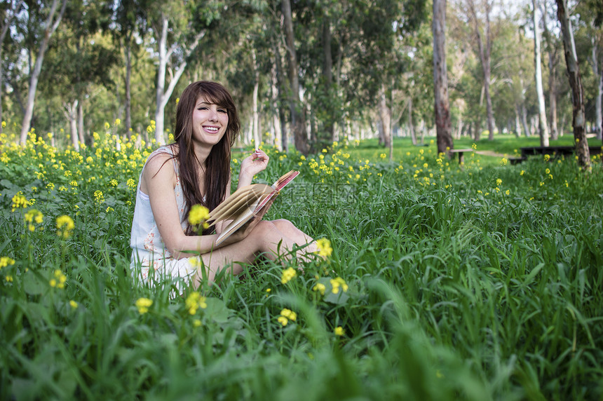 坐在森林里看书的年轻妇女图片