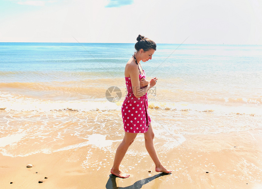 年轻妇女在海滩上行走图片