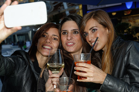 酒吧里用智能手机自拍的女性图片