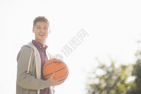 带着微笑拿着篮球的年轻男子肖像图片
