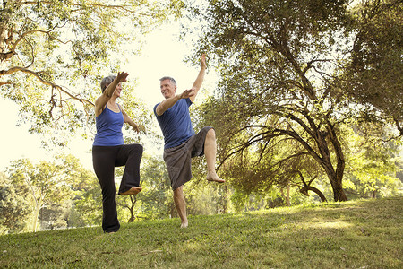 男人真人在公园里练习瑜伽姿势的成熟夫妇背景