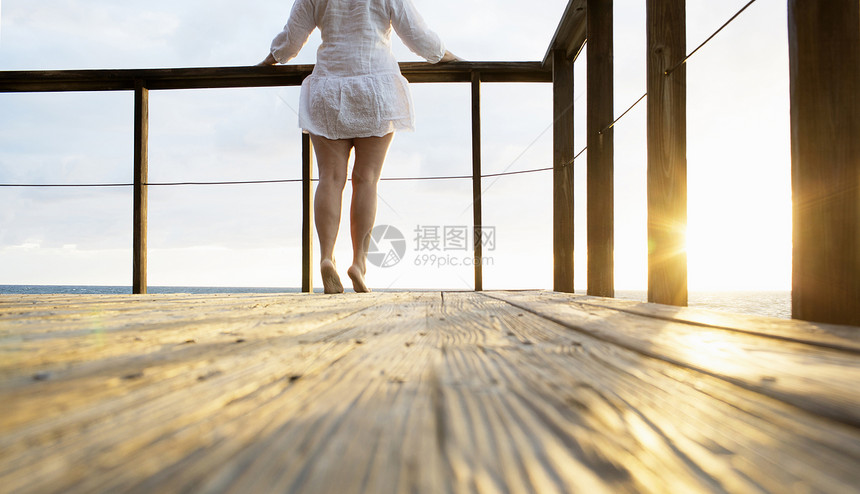 踮着脚尖在阳台上观看日出的年轻女性特写图片