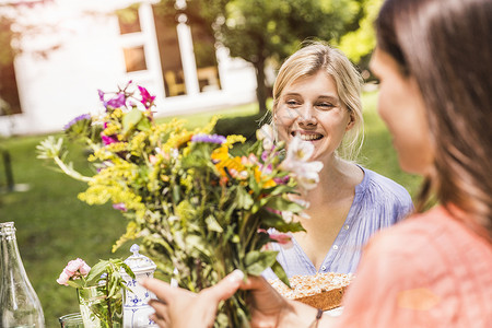 两位女性在花园看着一束花背景图片