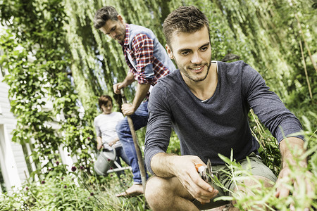 青年男子花园里修剪植物图片