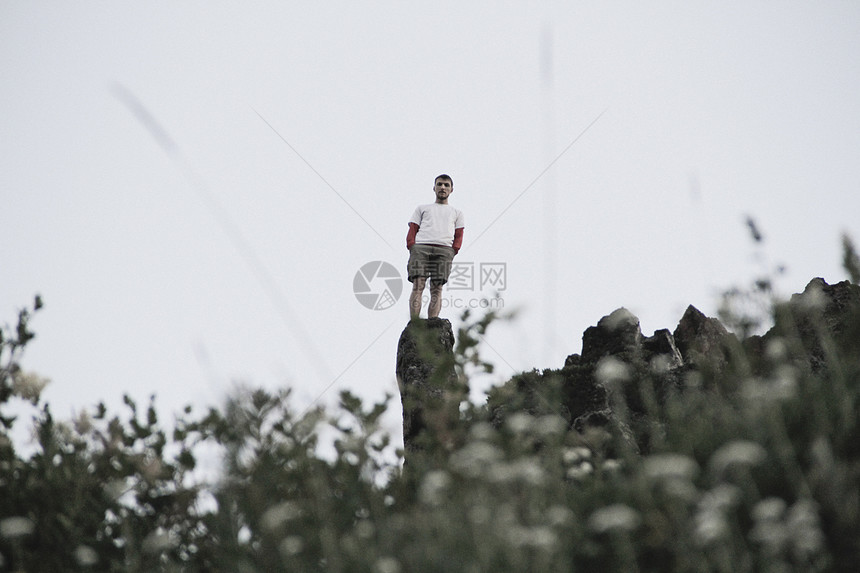 站在岩石顶端的年轻人图片