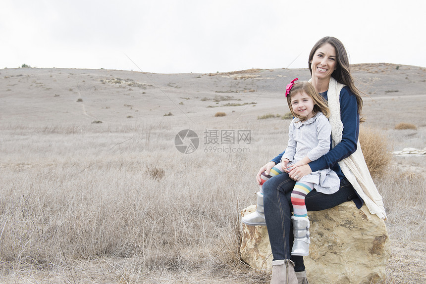 母亲和女儿坐在岩石上图片