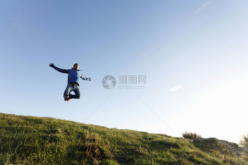 山顶上跳跃的徒步旅行者图片