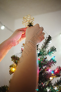 女人把星星放在圣诞树上图片